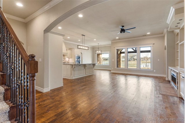 unfurnished living room with arched walkways, ceiling fan, stairway, and hardwood / wood-style flooring