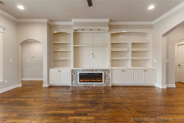 unfurnished living room featuring arched walkways, a fireplace, ornamental molding, wood finished floors, and baseboards