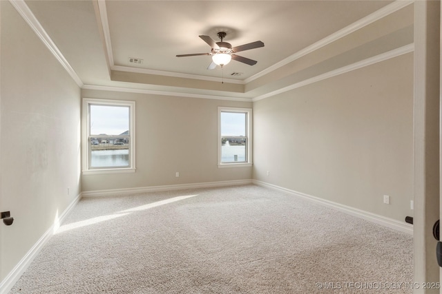 empty room with visible vents, baseboards, ornamental molding, a tray ceiling, and carpet floors