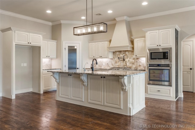 kitchen featuring dark wood-type flooring, light stone countertops, stainless steel appliances, premium range hood, and a sink