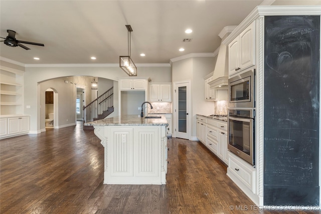 kitchen featuring stainless steel appliances, arched walkways, a sink, and dark wood-style floors