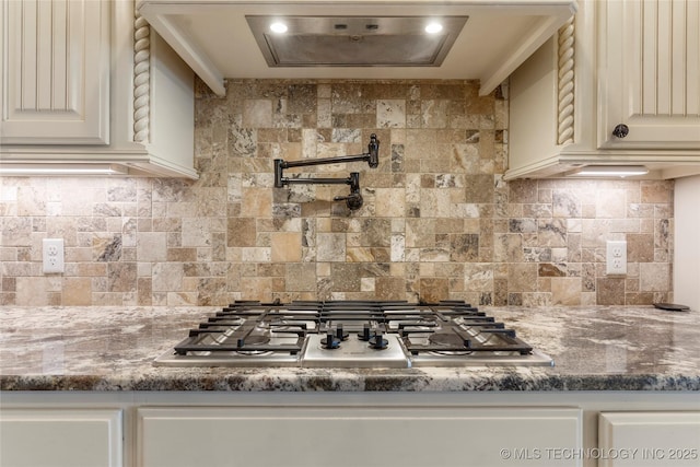 kitchen with stone counters, stainless steel gas cooktop, and backsplash