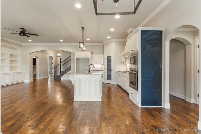 kitchen with arched walkways, stainless steel appliances, open floor plan, a sink, and ceiling fan