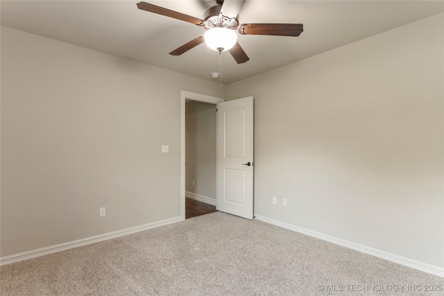 carpeted empty room featuring ceiling fan and baseboards