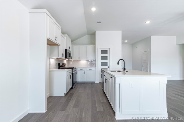 kitchen with light countertops, backsplash, appliances with stainless steel finishes, light wood-style floors, and a sink