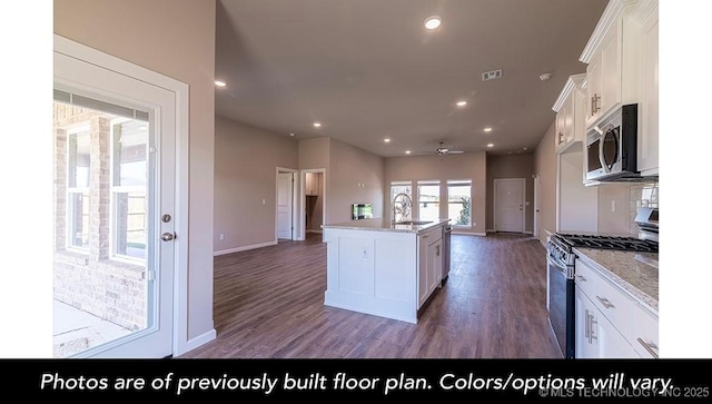 kitchen with appliances with stainless steel finishes, open floor plan, white cabinets, and wood finished floors