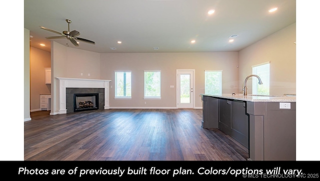 kitchen featuring baseboards, dark wood finished floors, light stone countertops, a fireplace, and recessed lighting