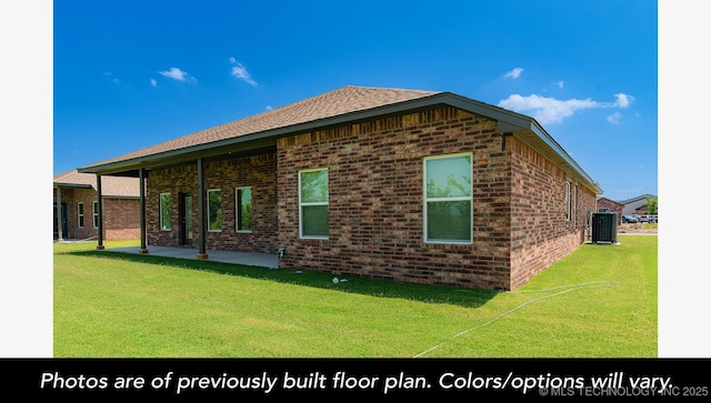 view of side of property with a yard, a patio, central AC, and brick siding