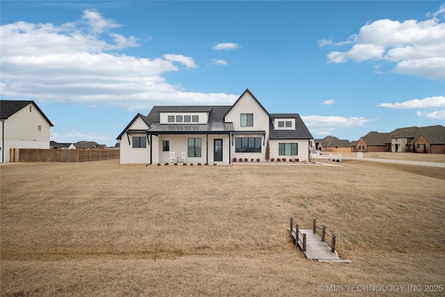 view of front of home with metal roof, a standing seam roof, a front yard, and fence