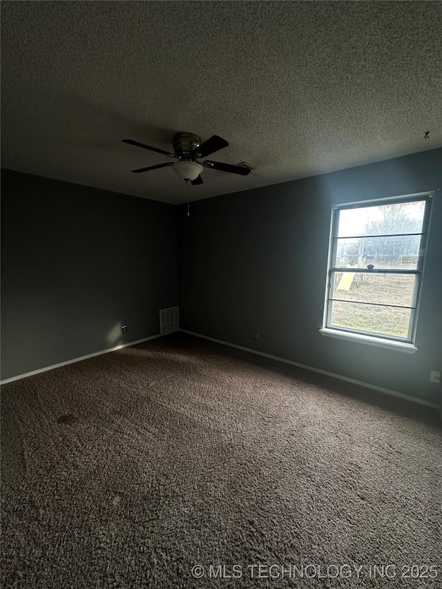 carpeted spare room with ceiling fan, a textured ceiling, visible vents, and baseboards