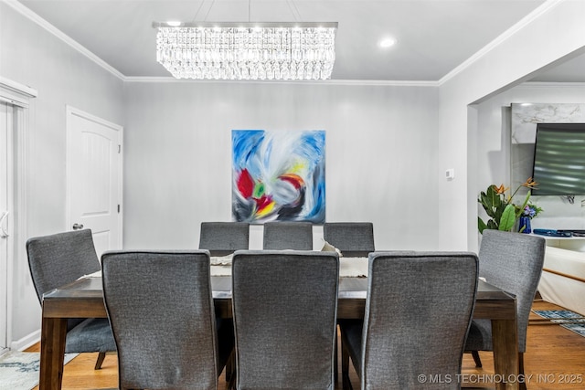 dining area with an inviting chandelier, crown molding, and wood finished floors