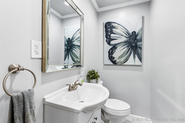 half bathroom with toilet, baseboards, ornamental molding, and vanity