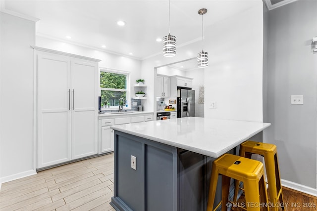 kitchen with white cabinets, a kitchen breakfast bar, a peninsula, stainless steel refrigerator with ice dispenser, and a sink