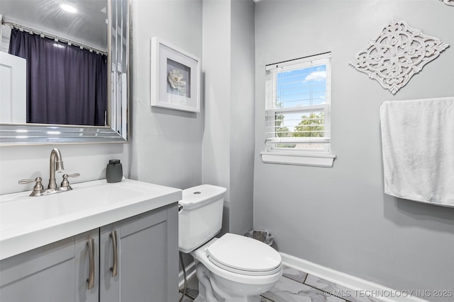 bathroom with toilet, marble finish floor, baseboards, and vanity