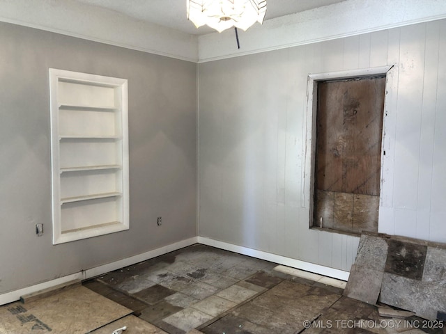 empty room with built in features and baseboards