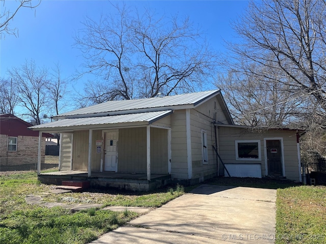 bungalow with a porch, metal roof, and fence