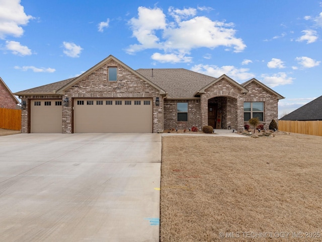 view of front of house with brick siding, a shingled roof, an attached garage, fence, and driveway