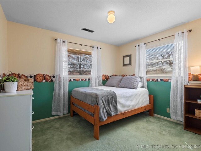 carpeted bedroom with visible vents, multiple windows, and baseboards