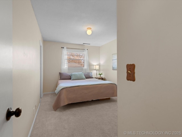 bedroom with baseboards and light carpet