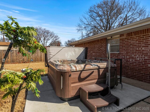 view of patio / terrace featuring a hot tub and fence