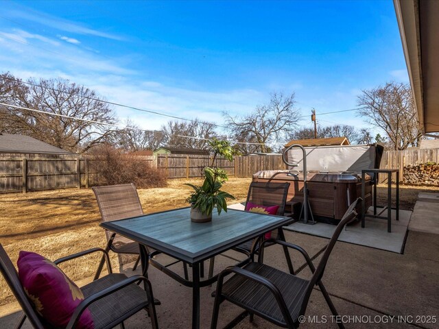 view of patio with outdoor dining space, a hot tub, and a fenced backyard