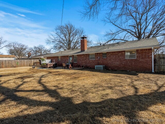 back of property featuring fence, a yard, brick siding, a chimney, and a patio area