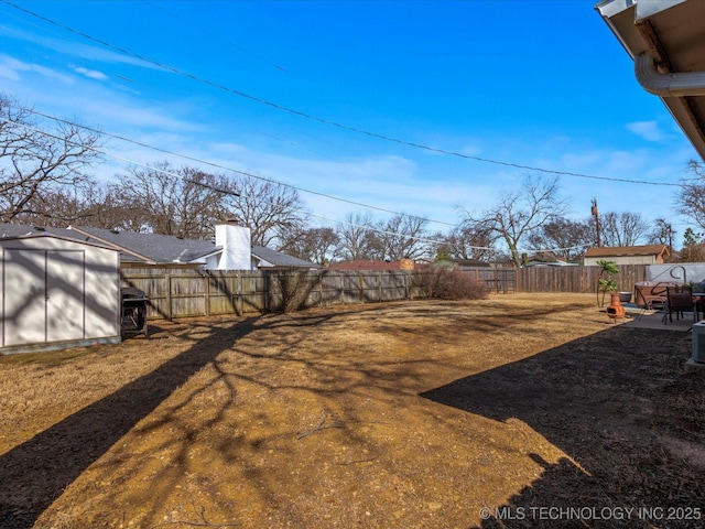 view of yard with an outdoor structure, a storage unit, a fenced backyard, and a patio