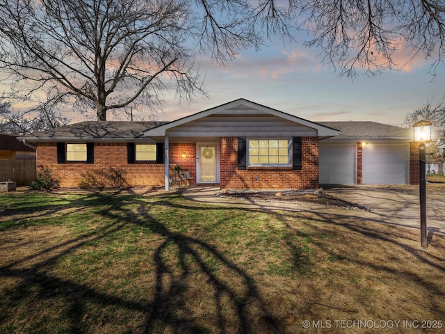 view of front facade with brick siding, a lawn, driveway, and an attached garage