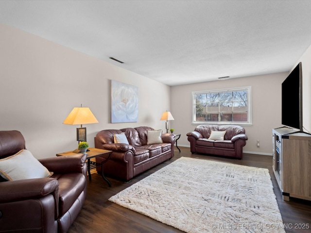 living room featuring visible vents, baseboards, and dark wood-style floors