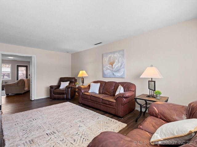 living area with visible vents, baseboards, and wood finished floors