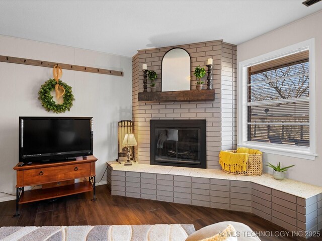 living area featuring a fireplace, wood finished floors, and visible vents