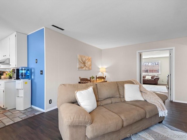 living area with dark wood-style floors, visible vents, and baseboards