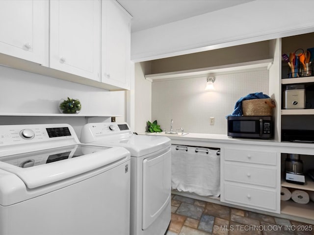 laundry room featuring washer and dryer, stone finish floor, cabinet space, and a sink