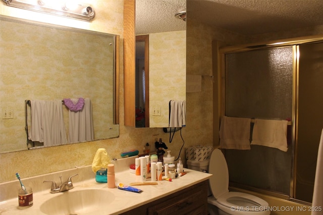 bathroom featuring toilet, a shower with door, a textured ceiling, and vanity