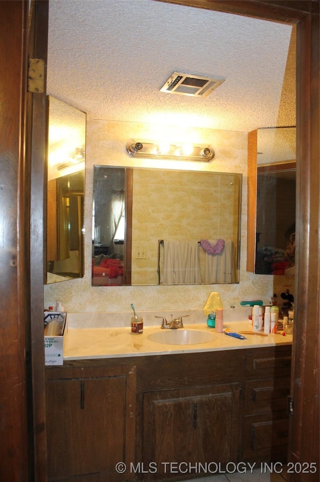 bathroom with visible vents, a textured ceiling, and vanity