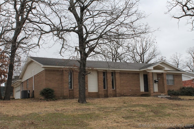 ranch-style home with cooling unit, brick siding, an attached garage, and a front yard