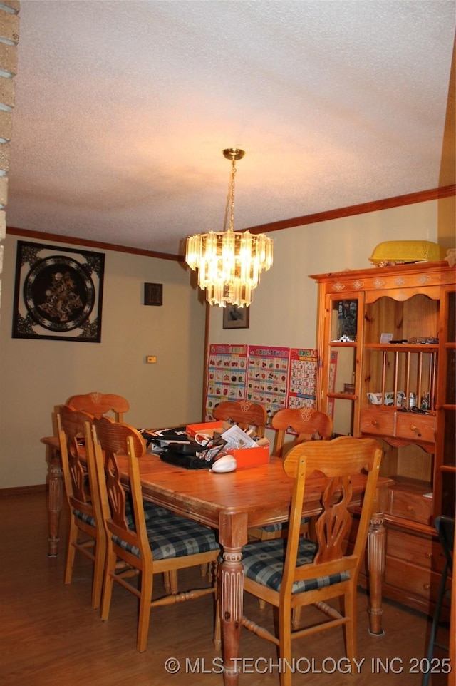 dining area with an inviting chandelier, a textured ceiling, crown molding, and wood finished floors