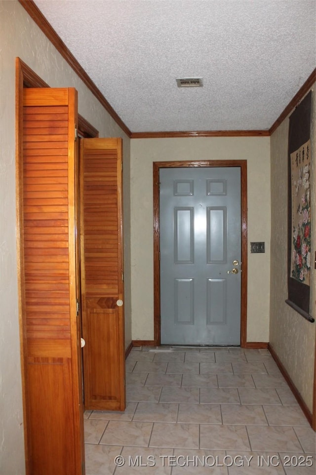 hallway with a textured ceiling, a textured wall, ornamental molding, and visible vents