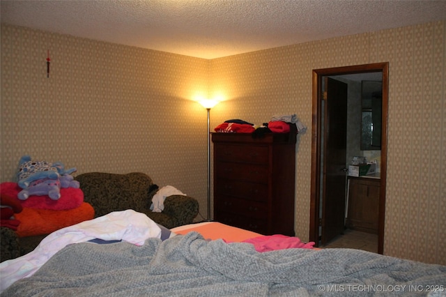 bedroom with a textured ceiling and wallpapered walls