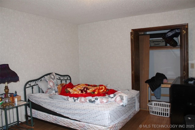 bedroom with a textured ceiling and wood finished floors