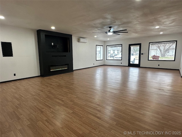 unfurnished living room with recessed lighting, wood finished floors, a fireplace, and a wall mounted AC