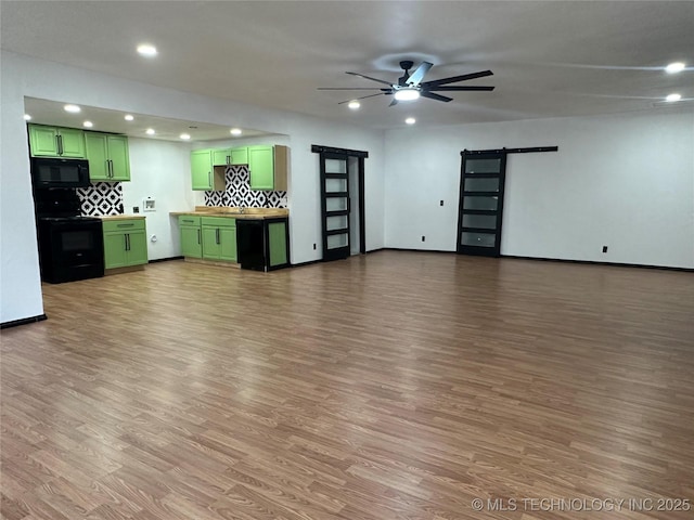 interior space featuring a barn door, wood finished floors, a ceiling fan, and baseboards