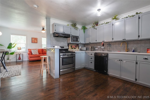 kitchen with stainless steel appliances, backsplash, dark wood finished floors, and under cabinet range hood
