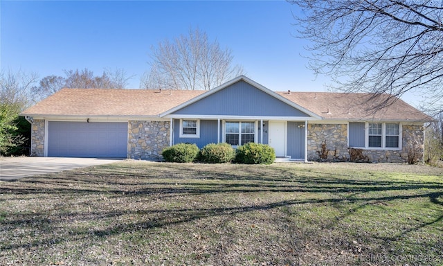 single story home with a garage, a front yard, concrete driveway, and stone siding