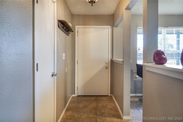 interior space with tile patterned flooring, a textured ceiling, and baseboards