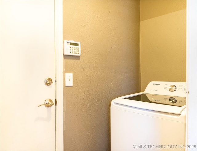 clothes washing area featuring washer / dryer, laundry area, and a textured wall