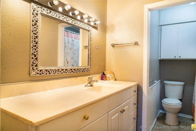 bathroom featuring toilet, a textured wall, and vanity