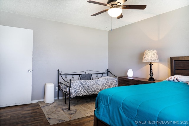 bedroom with ceiling fan, a textured ceiling, baseboards, and wood finished floors