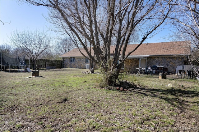 view of yard with a trampoline and fence