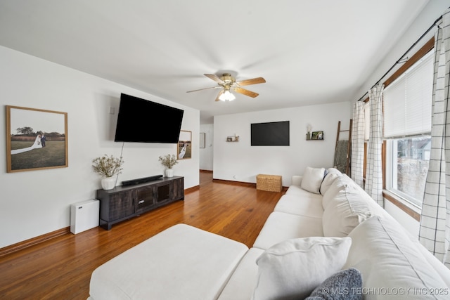 living room with ceiling fan, baseboards, and wood finished floors